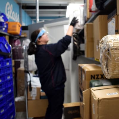 En person plockar upp paket i hyllan i en mataffär.