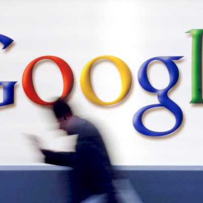 Mies kävelee vauhdilla Googlen logon ohi.