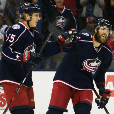 Två blåklädda ishockeyspelare firar mål i NHL.