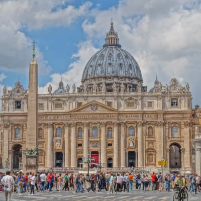 Petruskyrkan i Rom fotad mot en blå himmel, med hundratals turister på marken.