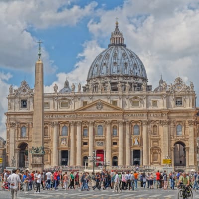 Petruskyrkan i Rom fotad mot en blå himmel, med hundratals turister på marken.