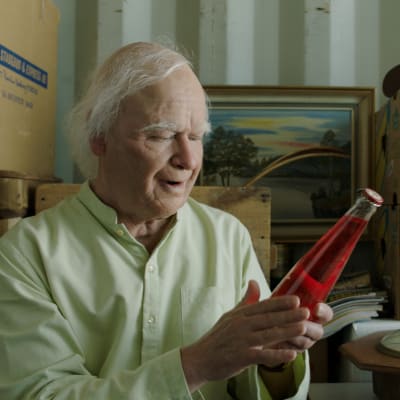 Allan (Robert Gustafsson) sitter i sitt lager och ser på en flaska Folksoda.