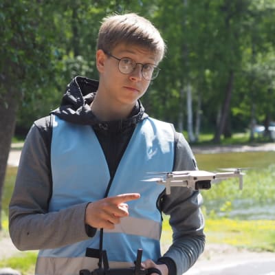 Inspiksen palkkaama droonin lennättäjä Arttu Kivimäki poseeraa ilmassa olevan droonin kanssa.