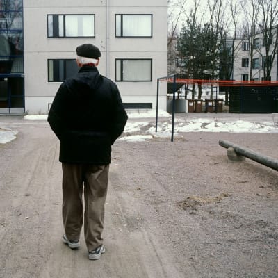 Äldre man går på gården
