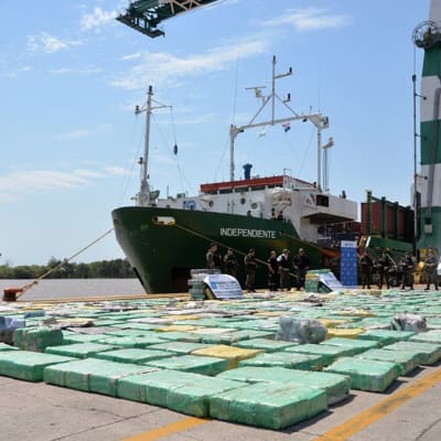 Åtta ton beslagtagen marijuana i gröna paket i hamnen bredvid en båt.