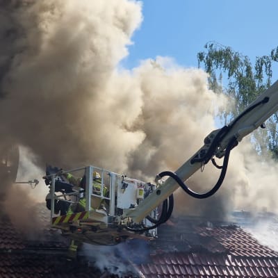 Brandkåren försöker släcka en husbrand från en lyftkran.
