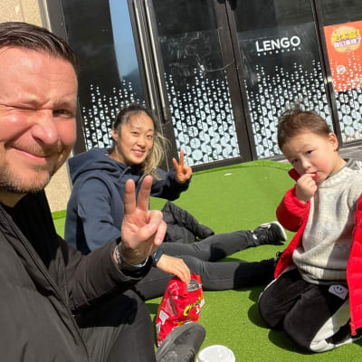 Marko Karsikon perhe istuu ulkona Shanghaissa ja poseeraa kameralle.