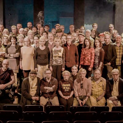 Ryhmäteatterilaisia ryhmäkuvassa lavalla. Kuva Mika Kaurismäen ohjaamasta dokumenttielokuvasta Ryhmäteatteri (2018).