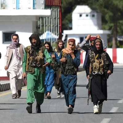Talibankrigare promenerar vid huvudingången till Kabuls flygplats.