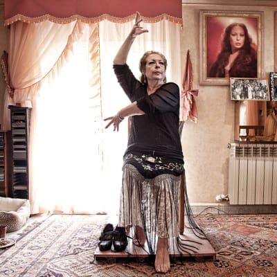 La Chana dansar flamenco sittandes i sitt vardagsrum.