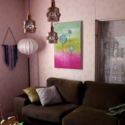 Vanhoja valaisimia, vihreä sohva ja taideteos olohuoneessa