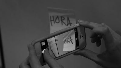 En mobiltelefon fotar en lapp med texten "hora".