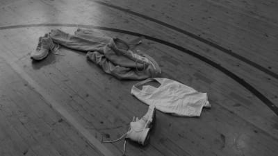 Kläder ligger på golvet i en gymnastiksal.