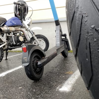 Mopeder och en elskoter står parkerade. 