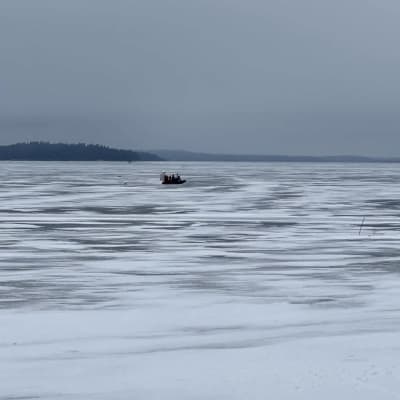 Kaukana vetisellä jäällä näkyy kumivene, jonka kyydissä on useita ihmisiä.