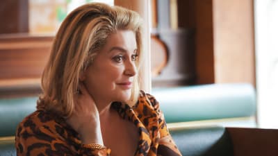 Catherine Deneuve vid ett cafébord.