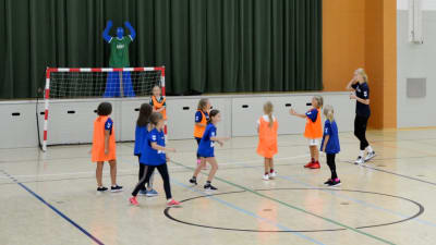 juniorer spelar handboll i en idrottshall.