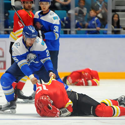 Ishockeyspelaren Damyr Ryspajev drar i skjortan på en motståndarspelare som ligger hjälplös på isen.