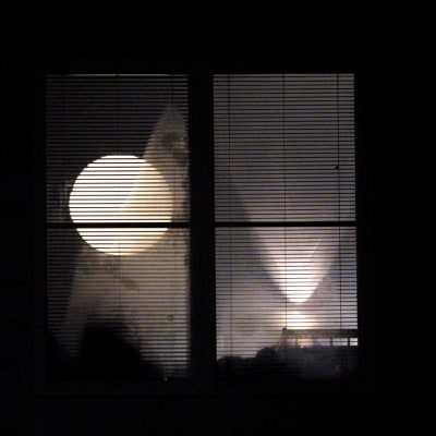 Yöllä otettu kuva ikkunasta, jossa loistaa valo. Joku valvoo.