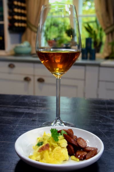 Omelett och chorizo på en tallrik, bakom tallriken ett vinglas med te i.