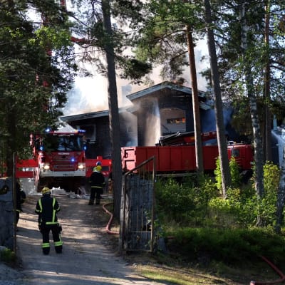 Ett hus som brinner som brandmän försöker släcka.