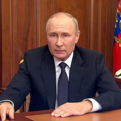 Vladimir Putin sitter vid ett bord.