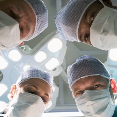 Fyra kirurger som tittar in i kameran ovanifrån.