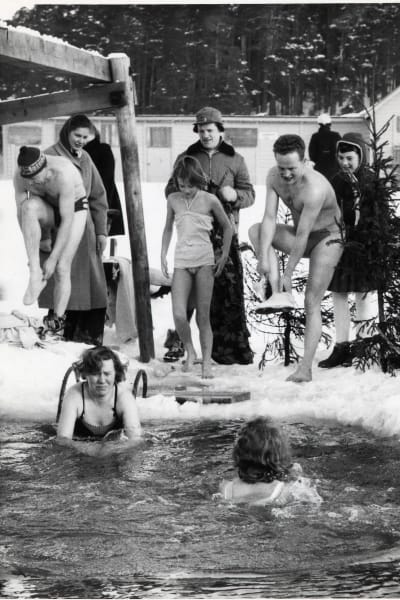 Svart-vit bild av Borgåbor som badar i en vak vid en badstrand på 1960-talet.