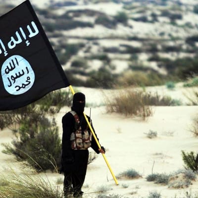Ihminen pitelee terroristijärjestö Isisin lippua.
