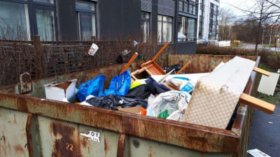 Smutsiga möbler in en sopcontainer.