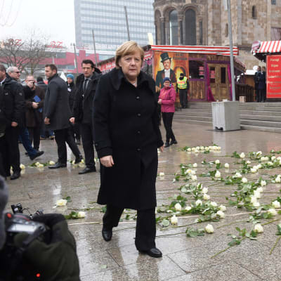 Angela Merkel, taustalla valkoisia ruusuja joulutorilla.