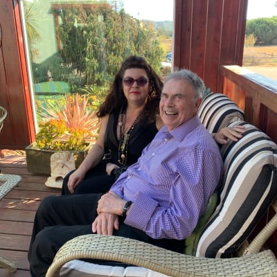 Nainen ja mies istuvat sohvalla keäsisellä verannalla. Taustalla avautuu pitkä näkymä kalifornialaiseen maisemaan.