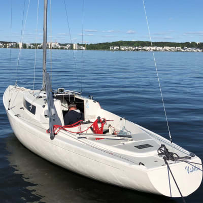 H-segelbåt i vattnet. Vädret är klart och små vågor rör sig på havsytan.