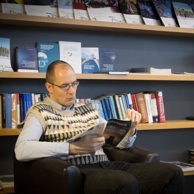 Kinaforskaren Rüüt Kaljula sitter i en stol och läser tidningen Diplomaatia.