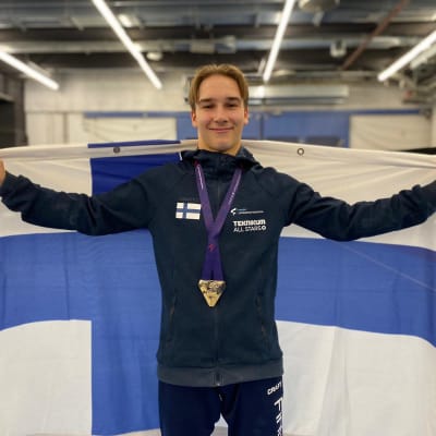 Joona Reiman mitalikaulassaja Suomen lippu harteillaan.