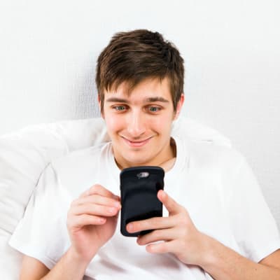 En kille underhåller sig genom att titta på sin telefon.