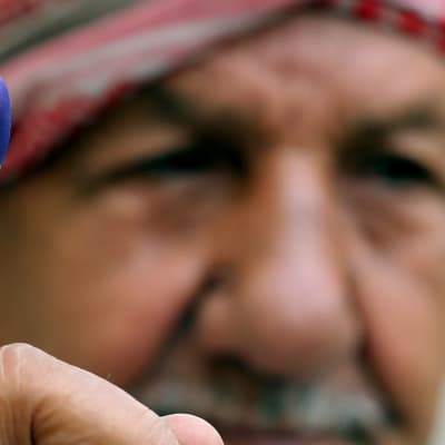 En irakisk man i Bagdad visar upp sitt bläckmärkta finger, beviset på att han röstat i lördagens val. 