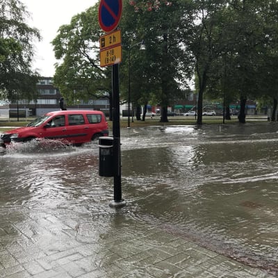 En bil kör genom cirka 30 centimeter djupt vatten i centrum av Raumo.