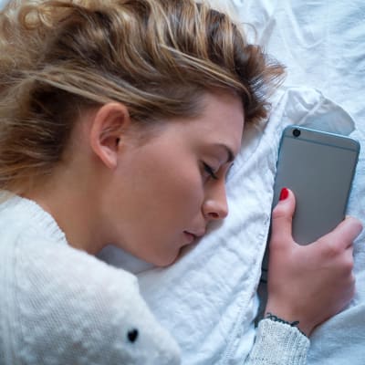 nainen nukkuu älypuhelimen vieressä