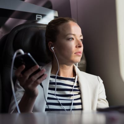 nuori nainen kuuntelee kuulokkeilla junassa