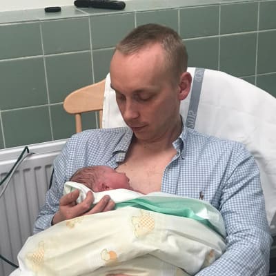 En pappa håller i ett nyfött barn