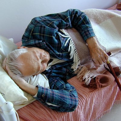 En gammal man vilar i en säng