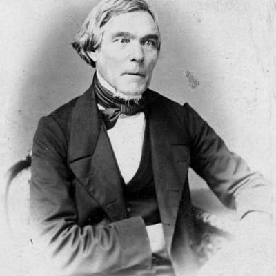 Mustavalkoinen valokuva Elias Lönnrotista istumassa.