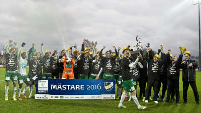 Jani Lyyski med mästarbucklan framför IFK Mariehamns spelare under guldfesten.