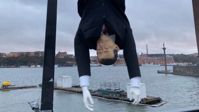 Erdogan-nukke roikkuu pää alaspäin Tukholmassa sillalla, taustalla meri