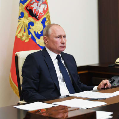 Vladimir Putin istuu työpöytänsä ääressä.