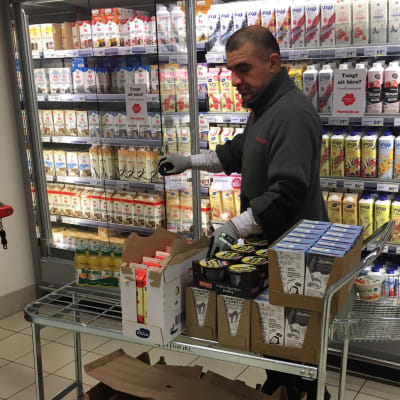 Butiksanställd plockar upp meijerivaror i en livsmedelsaffär.