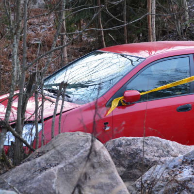 En liten röd bil med framändan på en stenhög. Bilen är lite tillknycklad framtill och har ett gult plastband om sig.