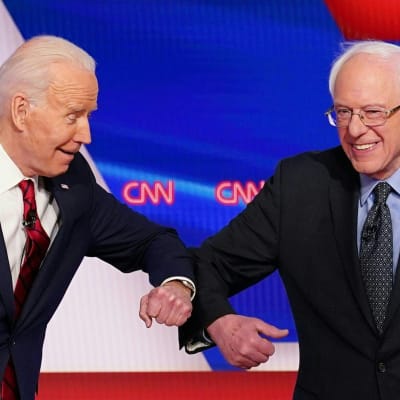 Två kostymklädda män ler mot varandra. Männen är Bernie Sanders och Joe Biden.