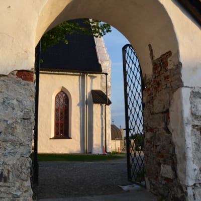 Genom kyrkporten syns en del av Borgå domkyrka i kvällssolen.